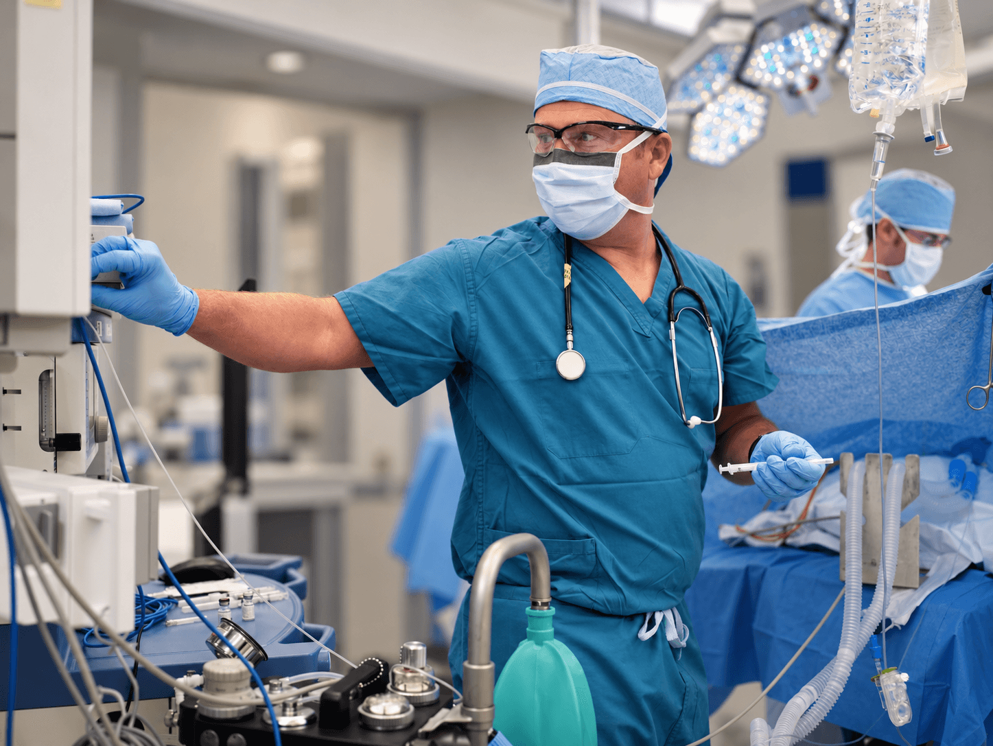 Anesthesia clinician adjusting equipment in an operating room.
