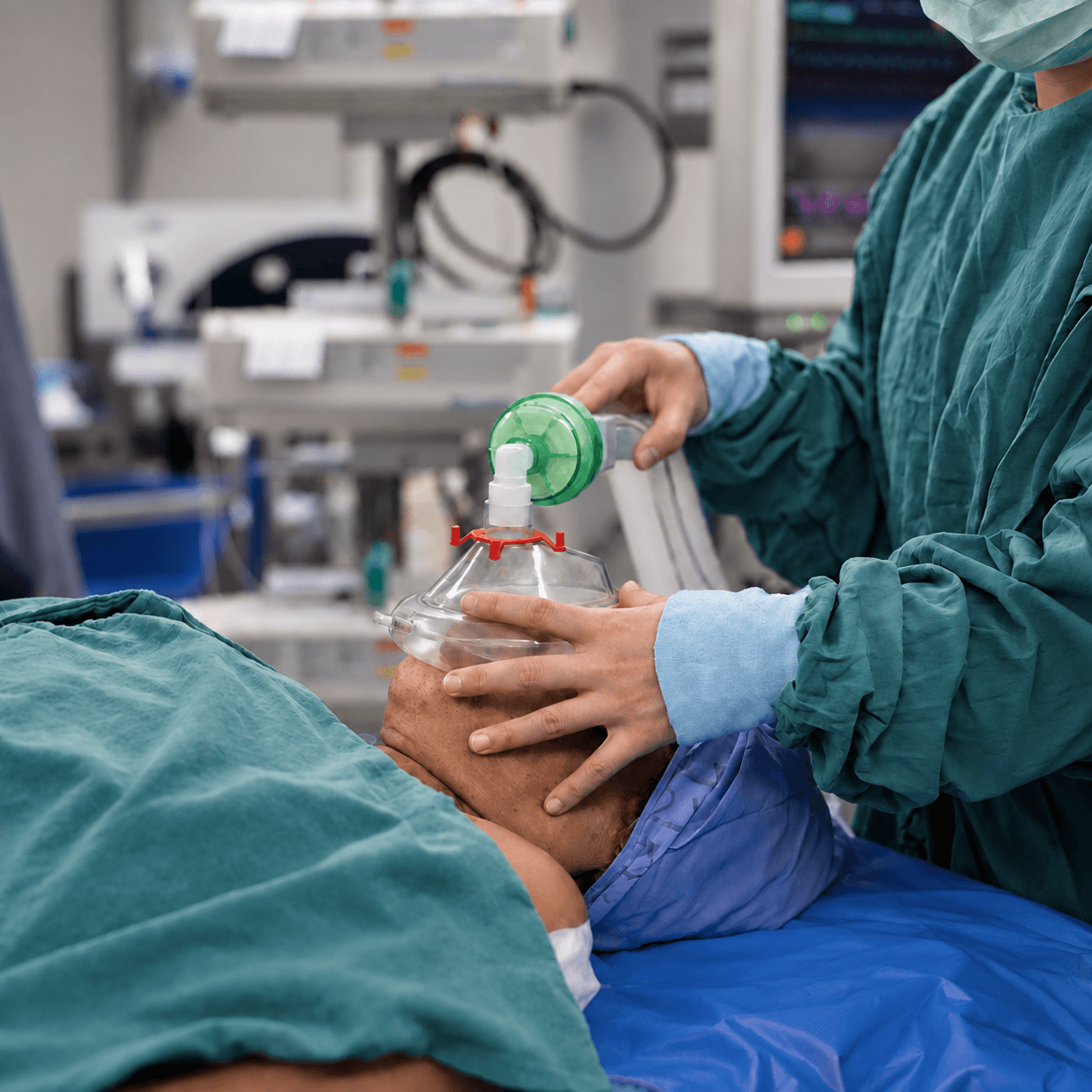 Anesthesia provider holding a ventilation mask over a patient's face.